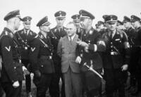 Bild vergrößern: Josef Bürckel  (im Anzug) neben Heinrich Himmler (rechts) und Reinhard Heidrich (links hinter Bürckel) bei der Ankunft auf dem Flugplatz in Lachen-Speyerdorf im Jahre 1932