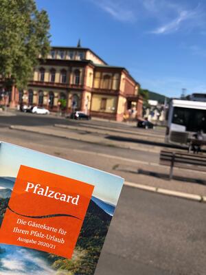 Bild vergrößern: PfalzCard im Hintergrund der Bahnhofsvorplatz
