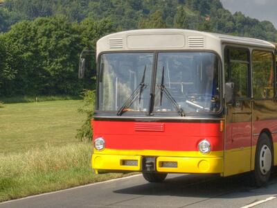 Bild vergr&ouml;&szlig;ern: Ein gelb-rot-gestrichener Bus fährt über die Landstraße.