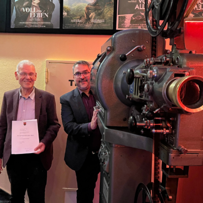 Oberbürgermeister Marc Weigel (rechts) gratuliert Roxy-Kino-Betreiber Michael Kaltenegger zur Auszeichnung durch das Land Rheinland-Pfalz