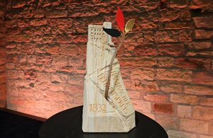 Bild vergr&ouml;&szlig;ern: Der Preis gefertigt aus hellem Sandstein und in Form eines Berges auf dem das Hambacher Schloss steht mit einem Baum mit drei Blättern in den Farben schwarz, rot, gold