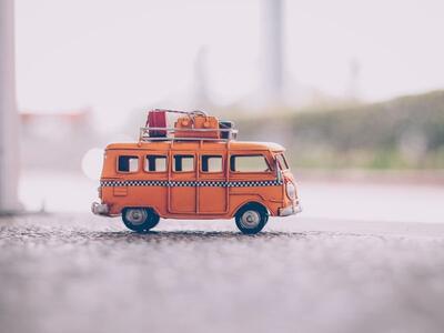 Bild vergr&ouml;&szlig;ern: Ein kleiner orangefarbener Bus mit Gepäck auf dem Dach
