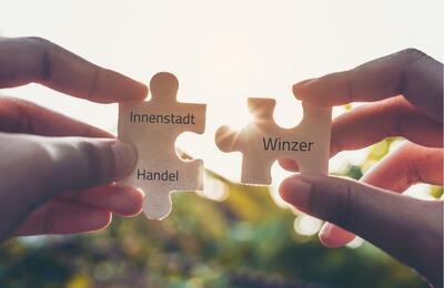 Bild vergr&ouml;&szlig;ern: Innenstadt & Händler Puzzlebild mit zwei Teilen in je einer Hand ein Teil - Winzer und Innenstadt-Handel