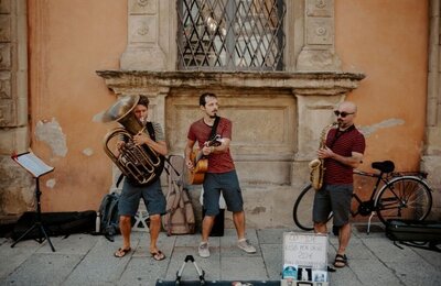 Bild vergr&ouml;&szlig;ern: Drei Musiker machen Straßenmusik in einer südeuropäischen Stadt