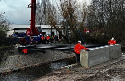 Bild vergr&ouml;&szlig;ern: Für die neue Brücke über den Speyerbach im Gelände der Landesgartenschau Neustadt an der Weinstraße wird ein Stahlelement wird mit Hilfe eines Krans eingehoben.