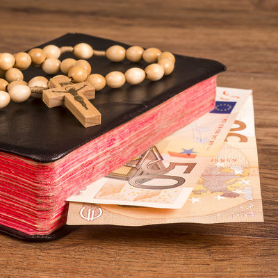 Bild vergrößern: Rosary lying on boards against the background of the book with euro banknotes