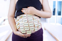 Bild vergrößern: Close up of pregnant belly with baby names on post-it