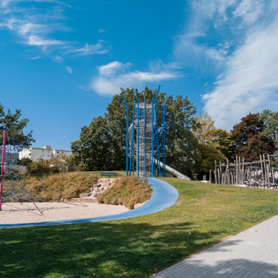 Bild vergr&ouml;&szlig;ern: Abenteuerspielplatz Böbig mit Blick auf eine Sandfläche mit Klettergerüst und blauem Gummi weg.