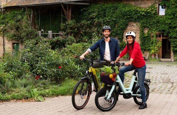 Bild vergr&ouml;&szlig;ern: Eine junge Frau und ein junger Mann stehen mit ihren Fahrrädern auf einem Hof. Die Frau hat frisches Obst und Gemüse in ihrem vorderen Fahrradkorb geladen. Das Bild verlinkt zu weiteren Informationen über die Veranstaltung "Stadtradeln" in Neustadt an der Weinstraße.