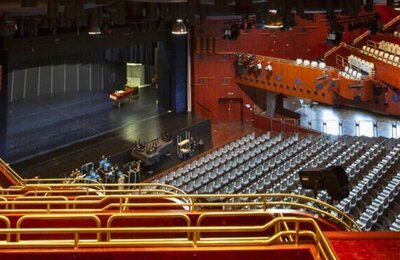 Auf dem Bild sieht man den Innenbereich der Stadthalle Saalbau mit Bühne und Bestuhlung.