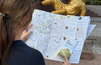 Bild vergr&ouml;&szlig;ern: eine Frau hält einen Stadtplan in der Hand und betrachtet diesen