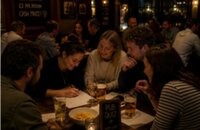 Bild vergr&ouml;&szlig;ern: Menschen sitzen gemeinsam zusammen, trinken Kaltgetränke, vor ihnen liegen die Quizfragen. Es wird gemeinsam gerätselt.