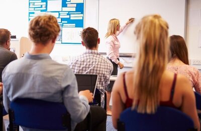 Bild vergr&ouml;&szlig;ern: Schülerinnen und Schüler blicken in einem Klassenraum zur Tafel.
