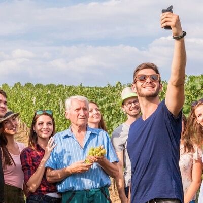 Bild vergr&ouml;&szlig;ern: Ein Mann macht ein Foto von einer Gruppe im Weinberg  – Gästeführungen für Gruppen